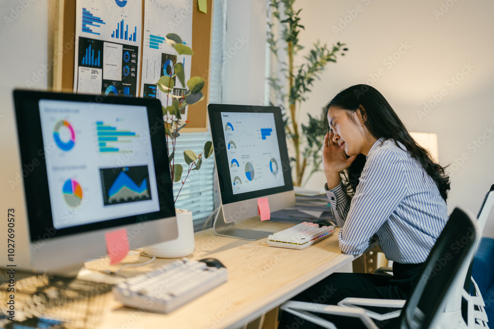 Young businesswoman is feeling tired and having a headache while using a computer at her desk in a modern bright office Young businesswoman is feeling tired and having a headache while using a computer at her desk in a modern bright office