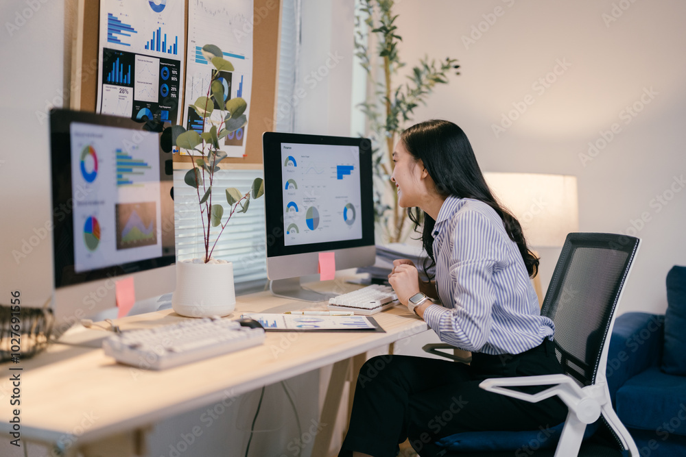 Young asian businesswoman in a modern office, happily analyzing data on her computer. She exudes success and professionalism, navigating the digital age to drive her company forward Young asian businesswoman in a modern office, happily analyzing data on her computer. She exudes success and professionalism, navigating the digital age to drive her company forward