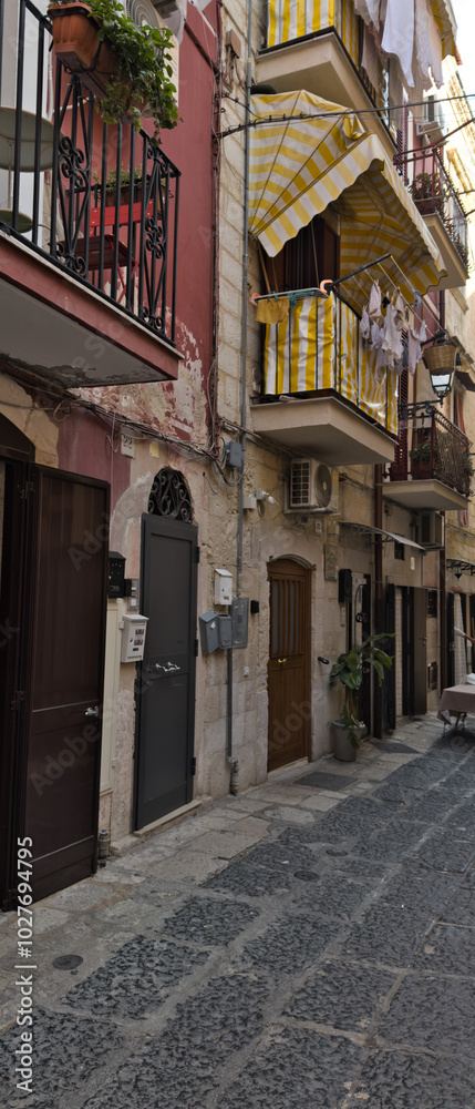 Naklejka premium Narrow street in the old town center. Architecture of historic tenement houses in the Italian city. Bari, Puglia, Italy.