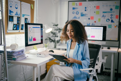 Focused african american businesswoman analyzes financial data in a modern office, exuding confidence and determination