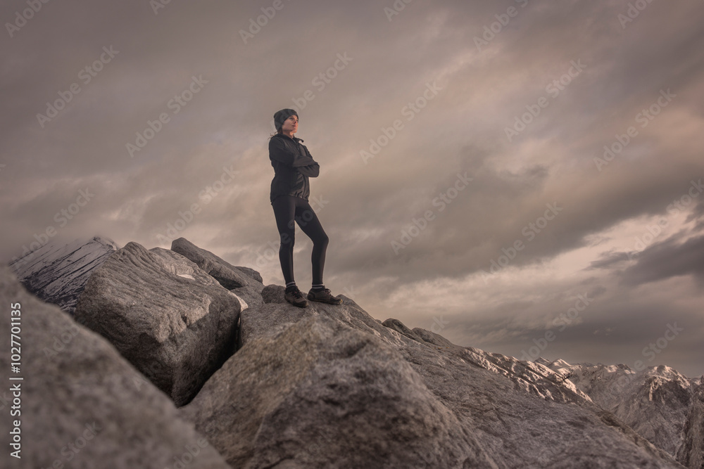 Obraz premium Woman standing on a rocky mountain looking at the view