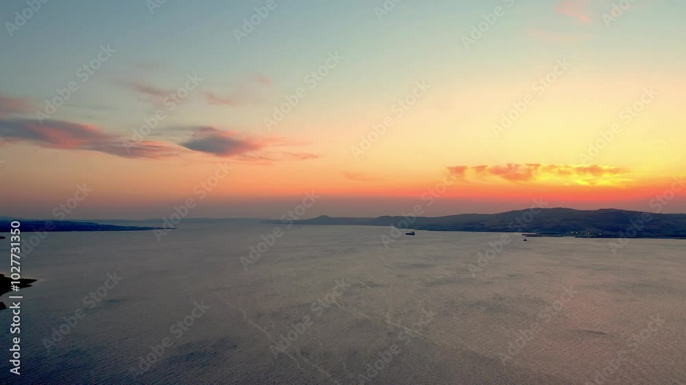 As the sun sets, golden hues shimmer on the calm waters of the Çanakkale Strait, where cargo ships gracefully glide, creating a captivating scene. As the sun sets, golden hues shimmer on the calm waters of the Çanakkale Strait, where cargo ships gracefully glide, creating a captivating scene.
