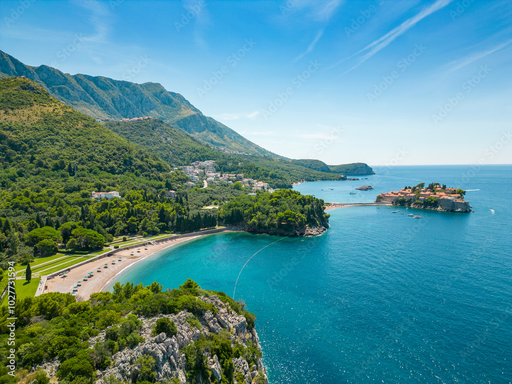 Aerial drone view of Sveti Stefan Island- Luxury travel destination in Montenegro. Waves splashing the rocks. At right is Sveti Stefan Beach. Panoramic view. Emerald water. Aerial drone view of Sveti Stefan Island- Luxury travel destination in Montenegro. Waves splashing the rocks. At right is Sveti Stefan Beach. Panoramic view. Emerald water.