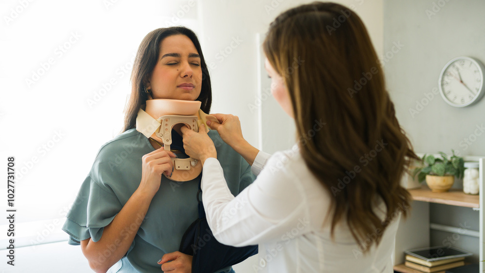 Female doctor gently applying a cervical collar to a patient with neck pain following an accident Female doctor gently applying a cervical collar to a patient with neck pain following an accident