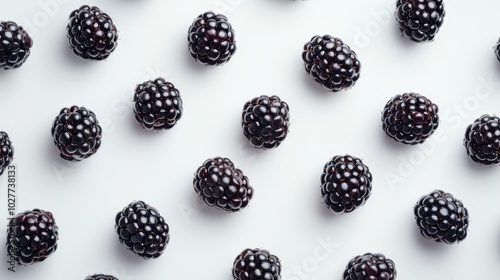 Multiple blackberries arranged in a pattern on a white surface