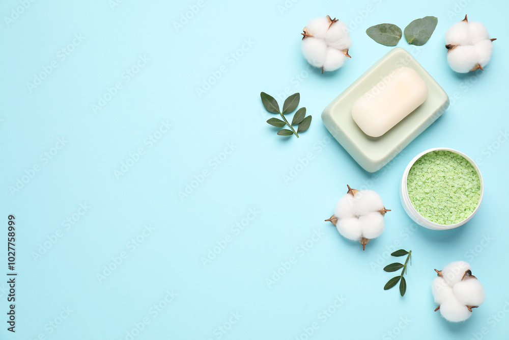 Different cosmetic products, leaves and cotton flowers on light blue background, flat lay. Space for text Different cosmetic products, leaves and cotton flowers on light blue background, flat lay. Space for text