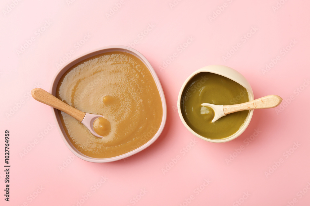 Delicious baby food and spoons in bowls on pink table, flat lay Delicious baby food and spoons in bowls on pink table, flat lay
