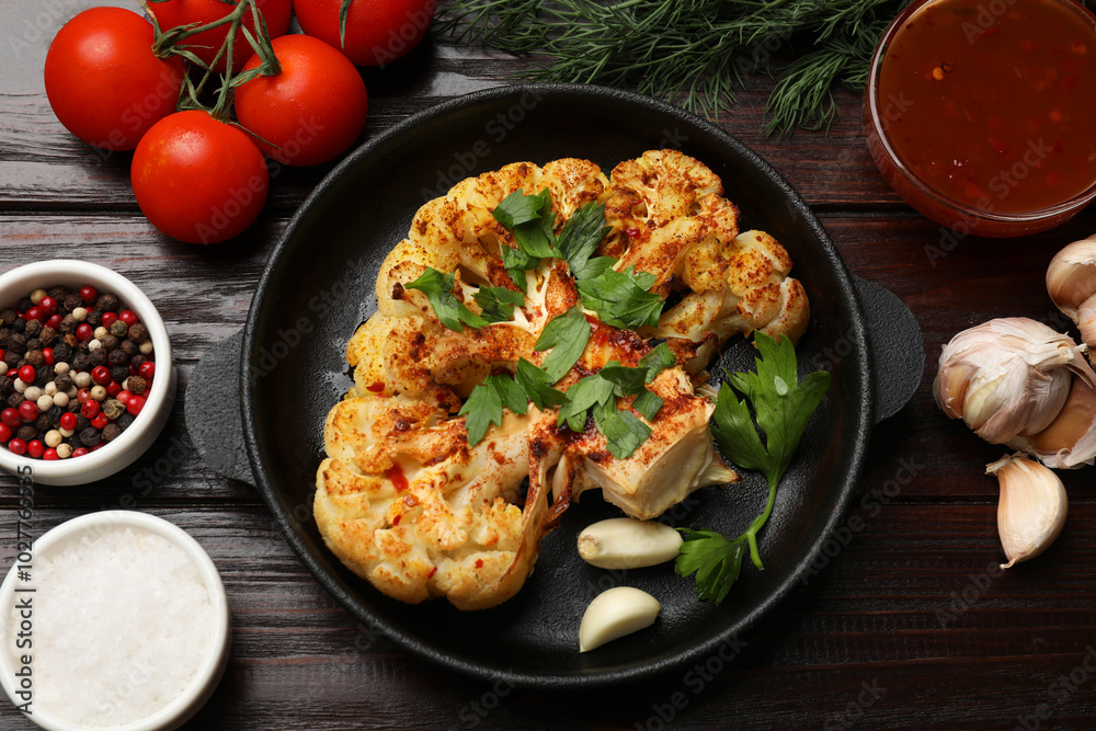 Tasty cauliflower steak in frying pan and other products on wooden table, top view Tasty cauliflower steak in frying pan and other products on wooden table, top view