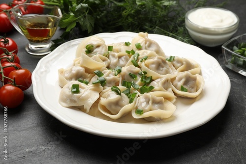 Delicious pelmeni with green onion served on grey table