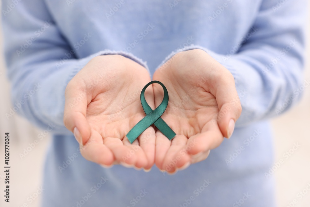 Woman with teal ribbon on light background, closeup. Ovarian cancer and gynecological disorders awareness Woman with teal ribbon on light background, closeup. Ovarian cancer and gynecological disorders awareness