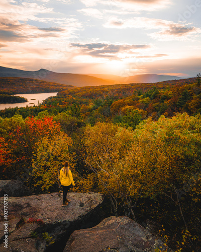 Beautiful Female Adventure Travel Hiker Yellow Coat Stands on Rock Wide View Sunset Rock Catskills New York New England Fall Foliage Autumn Season