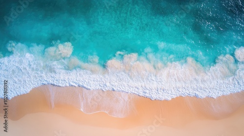 Drone shot capturing bright turquoise water with gentle waves and a sandy beach, all bathed in sunshine