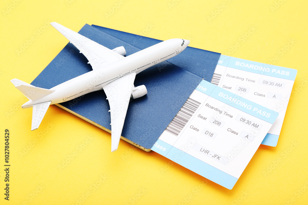 Passports with boarding passes and airplane model on yellow background