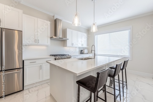 High-end modern kitchen with white cabinets, sleek island, and stainless steel finishes, illuminated by elegant pendant lighting