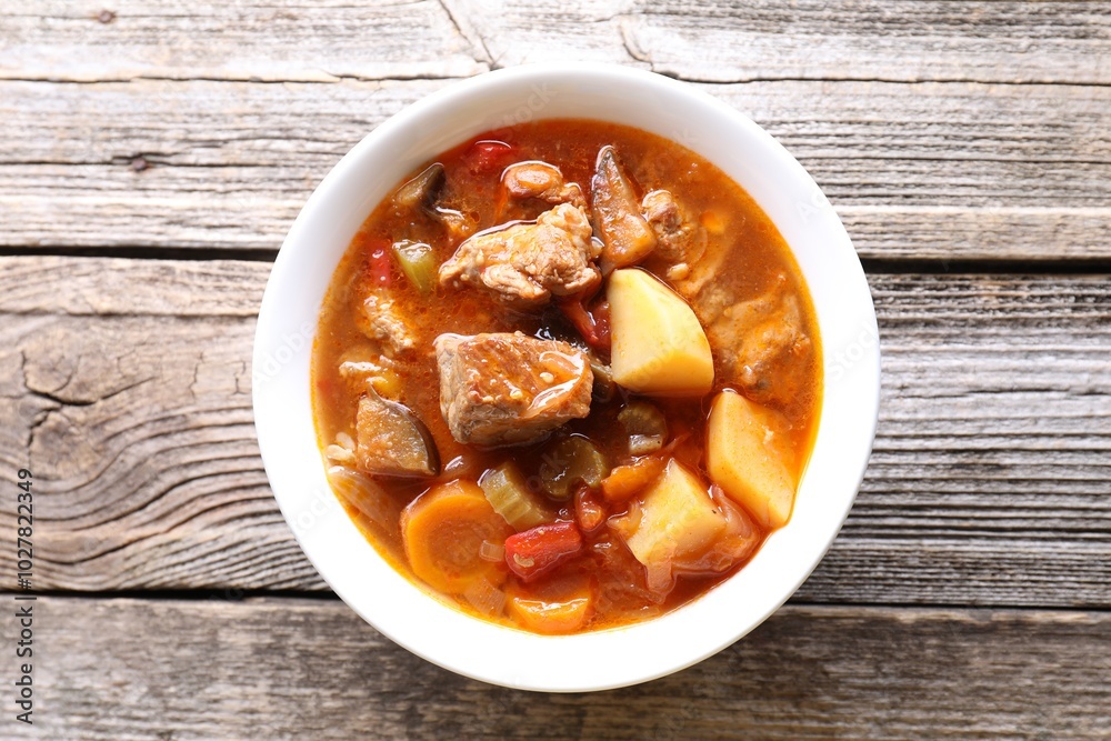 Delicious stew with vegetables in bowl on wooden table, top view Delicious stew with vegetables in bowl on wooden table, top view