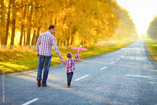 A Happy parent walks along the road with a child and an airplane in the park on nature travel