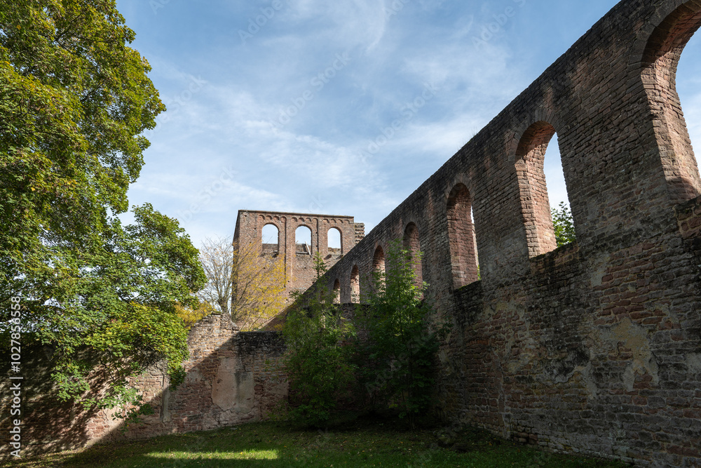 A stone wall with arched windows stands tall against a blue sky, remnants of a historic building in Germany A stone wall with arched windows stands tall against a blue sky, remnants of a historic building in Germany