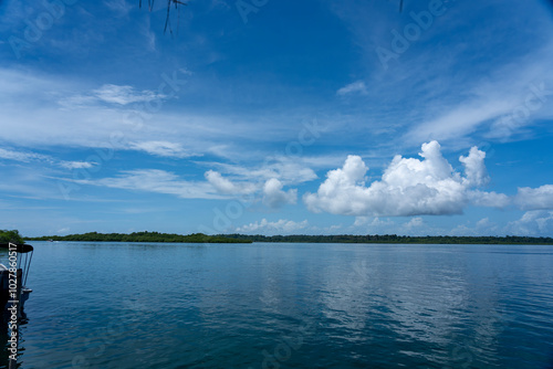 Beautiful island scenery with a bright blue sky, green foliage, and calm waters reflecting the natural beauty of the coastline, environment for travel, summer vacations, peaceful retreats photo