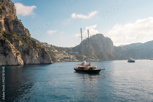 Sailboat and Yachts Docked Near the Rocky Coast of Capri, Italy – Idyllic Mediterranean Scene