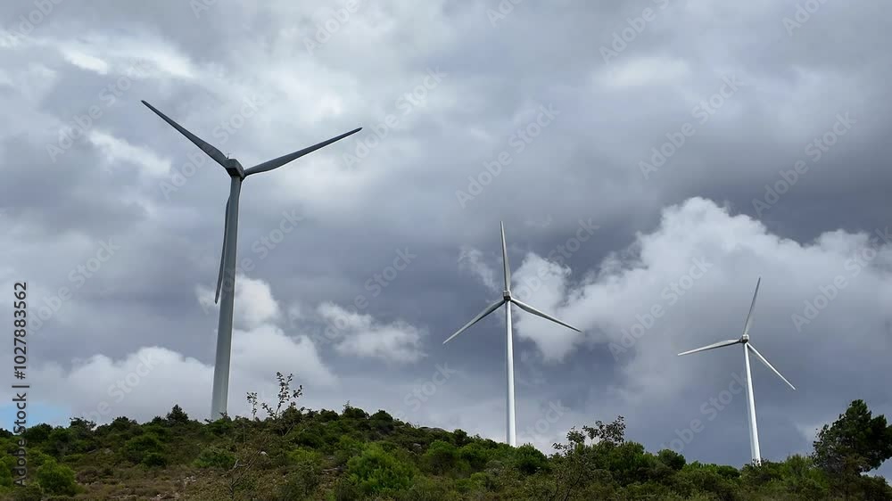Wind turbines for alternative electricity, energy and power surrounded by stormy clouds and landscape, ecology and environment concept Wind turbines for alternative electricity, energy and power surrounded by stormy clouds and landscape, ecology and environment concept