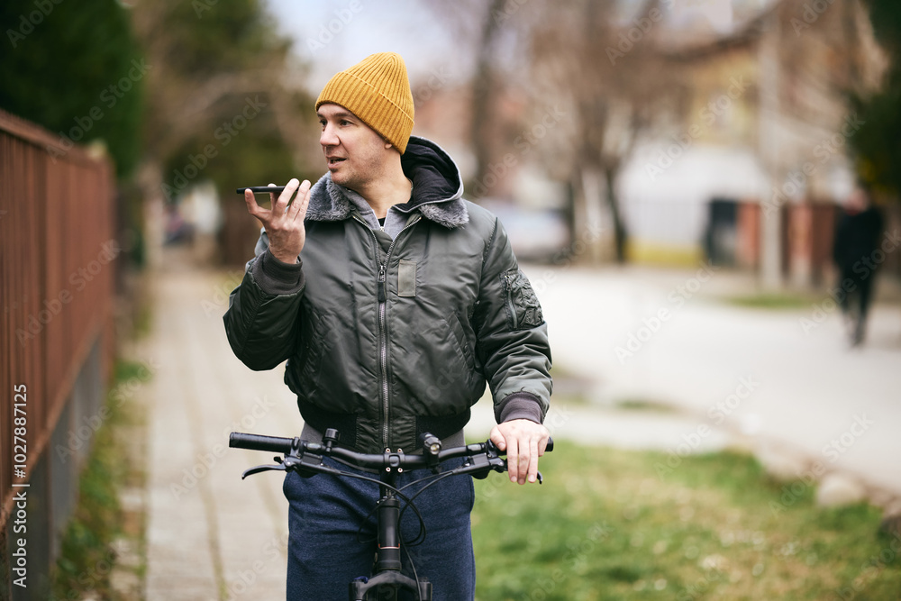Naklejka premium Man Recording Voice Message While Leaning on a Bicycle