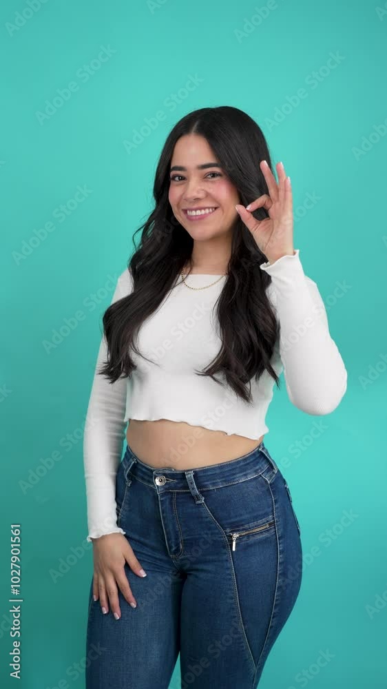 Portrait of a latina woman in a studio making the ok sign with hand Portrait of a latina woman in a studio making the ok sign with hand