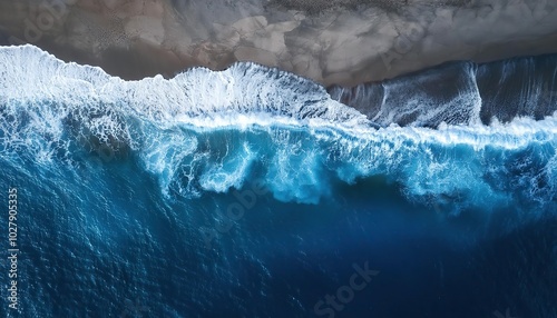 ocean waves and foam splashing on the dark navy blue or gray sand beach