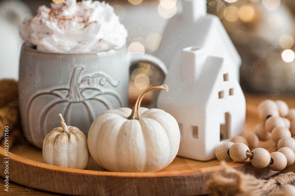 Delicious pumpkin latte with whipped cream and cinnamon in a mug on the table in the living room interior. Autumn decor in the house. Scandinavian style.