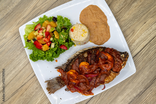 Overhead view of grilled mojarra fish with spicy shirmp diablo dinner served with rice and beans on a wooden platter photo