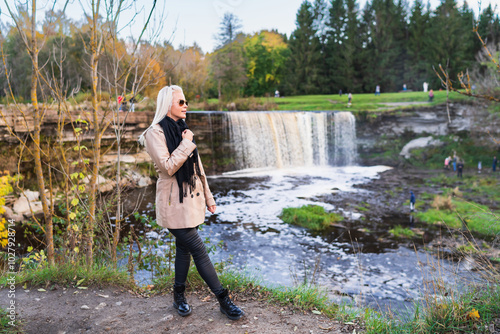 Slender blonde girl in nature near Jagala waterfall on a spring evening. Nature of Estonia. photo