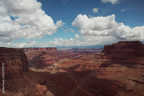 Desert Mesas Descending into a Valley Under a Blue Sky with Puffy Clouds