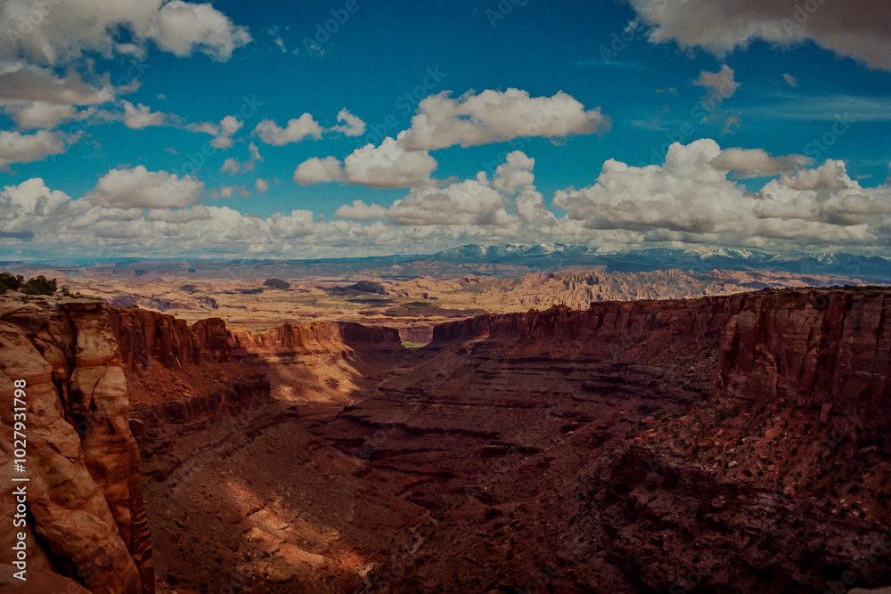Desert Mesas Sloping Down into a Valley Beneath a Bright Blue Sky with Fluffy Clouds Desert Mesas Sloping Down into a Valley Beneath a Bright Blue Sky with Fluffy Clouds