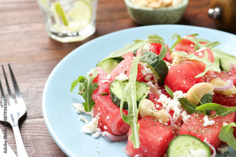 Tasty salad with watermelon, feta cheese, cashews and arugula on wooden table, closeup Tasty salad with watermelon, feta cheese, cashews and arugula on wooden table, closeup