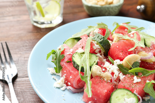 Tasty salad with watermelon, feta cheese, cashews and arugula on wooden table, closeup