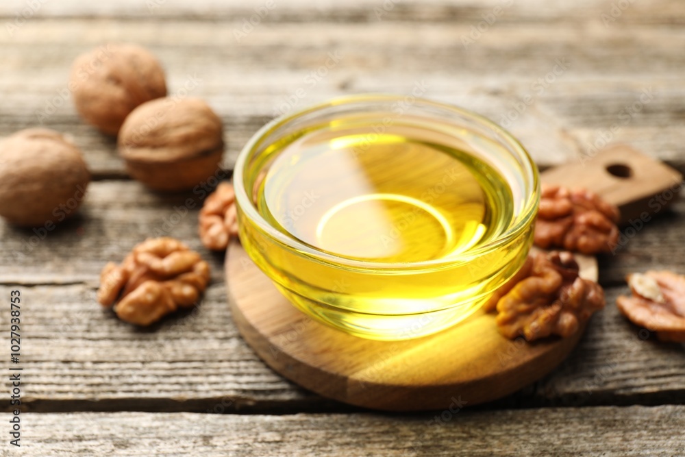 Cooking oil in bowl and walnuts on wooden table, closeup Cooking oil in bowl and walnuts on wooden table, closeup