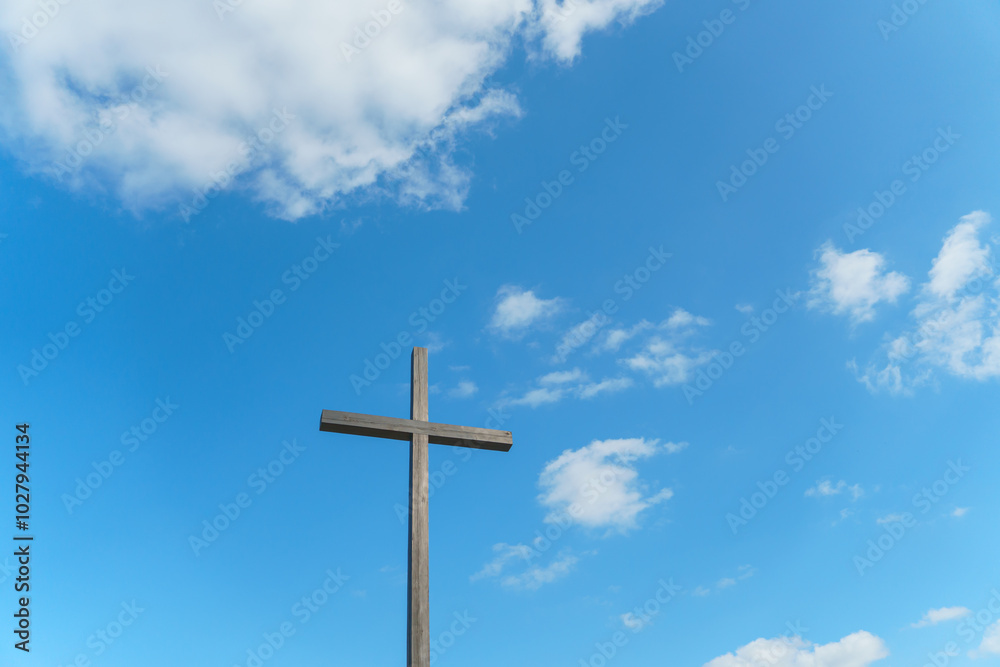 An Orthodox wooden cross on a background of blue sky and clouds. An old antique cross close-up. An Orthodox wooden cross on a background of blue sky and clouds. An old antique cross close-up.