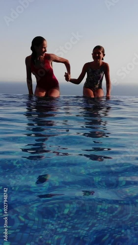 two girls jumping off the edge of an infinity pool
