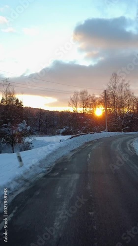 Traveling by car on a winter road at sunset, vertical