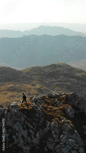 Strong independent woman walking on a mountain ridge.