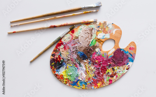 Fototapeta Naklejka Na Ścianę i Meble -  Art palette with colorful paint strokes and paintbrushes on white isolated background, top view, flat lay, object