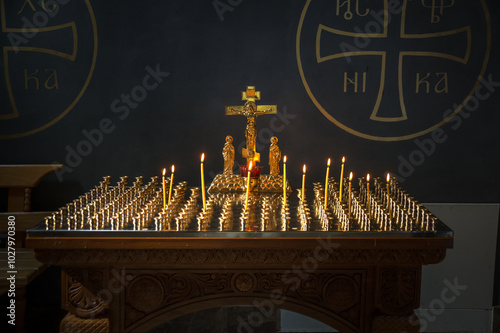 Lighted candles on a stand with golden crusifix in Russian Orthodox Christian cathedral