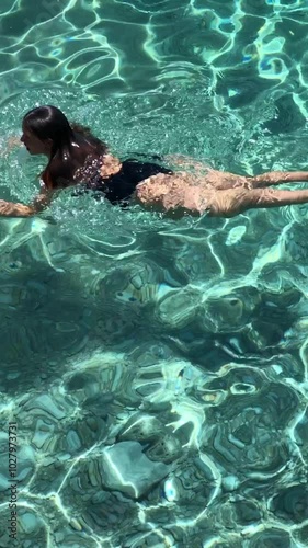 Girl swimming underwater in a transparent green blue sea