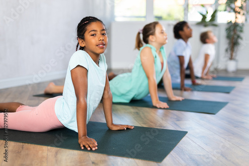 School kids meditating during yoga class. Yoga pose bhudjangasana. photo