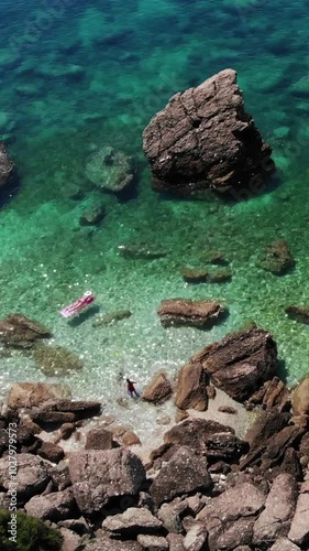 Aerial view of transparent blue sea shore whith young woman relaxing on waves