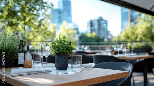 A modern terrace dining area with neatly set tables and chairs, surrounded by lush green plants, provides a breathtaking view of the urban cityscape. photo