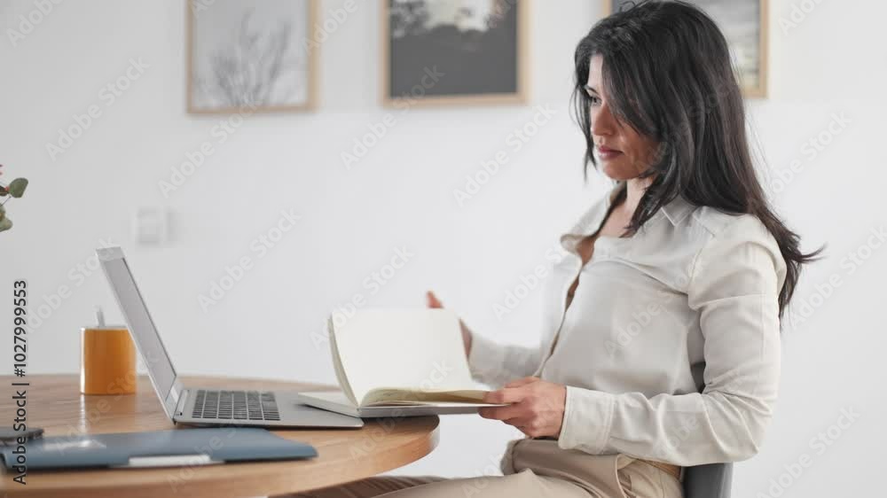Businesswoman works at her laptop, taking notes and managing tasks in a modern home office environment Businesswoman works at her laptop, taking notes and managing tasks in a modern home office environment