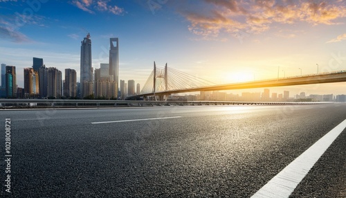 asphalt highway road and bridge with modern city skyline at sunrise