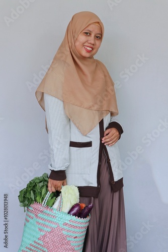 Young Muslim woman happily shopping for vegetables photo