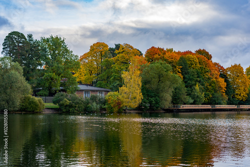 House among colorful trees on the lake shore, autumn landscape