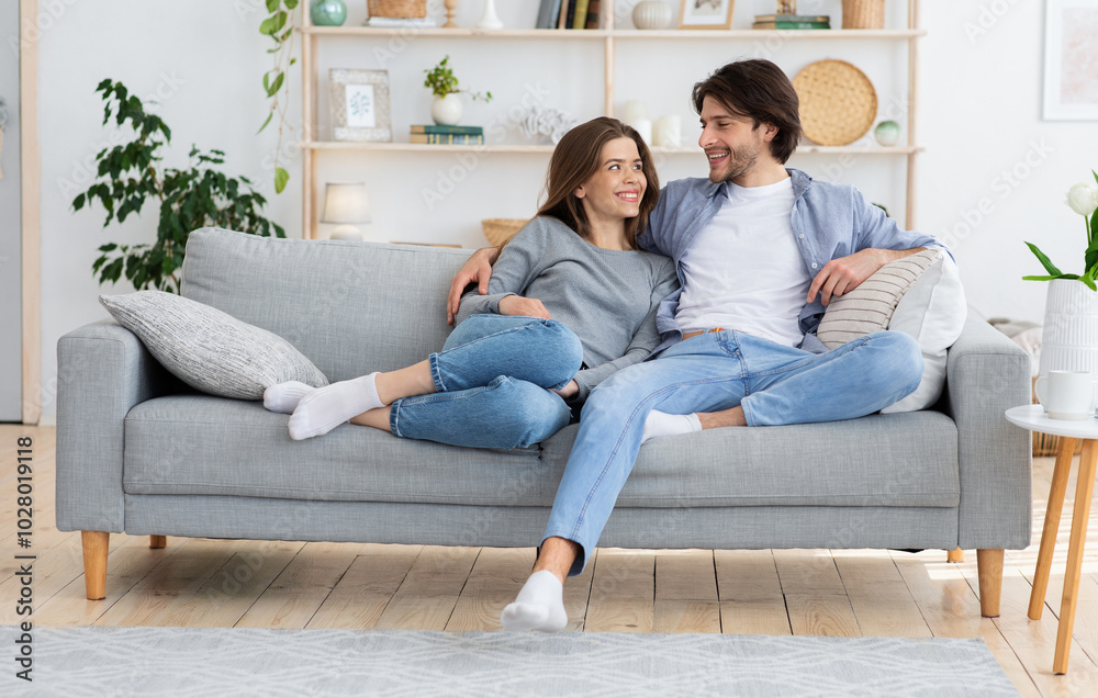 Young couple in love hugging on sofa at home, looking at each other, enpty space Young couple in love hugging on sofa at home, looking at each other, enpty space